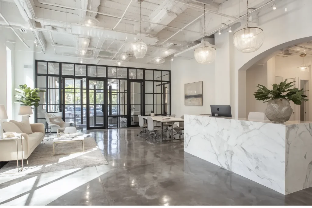 Espace d'accueil moderne d'une agence immobilière de luxe avec comptoir en marbre blanc et éclairage élégant