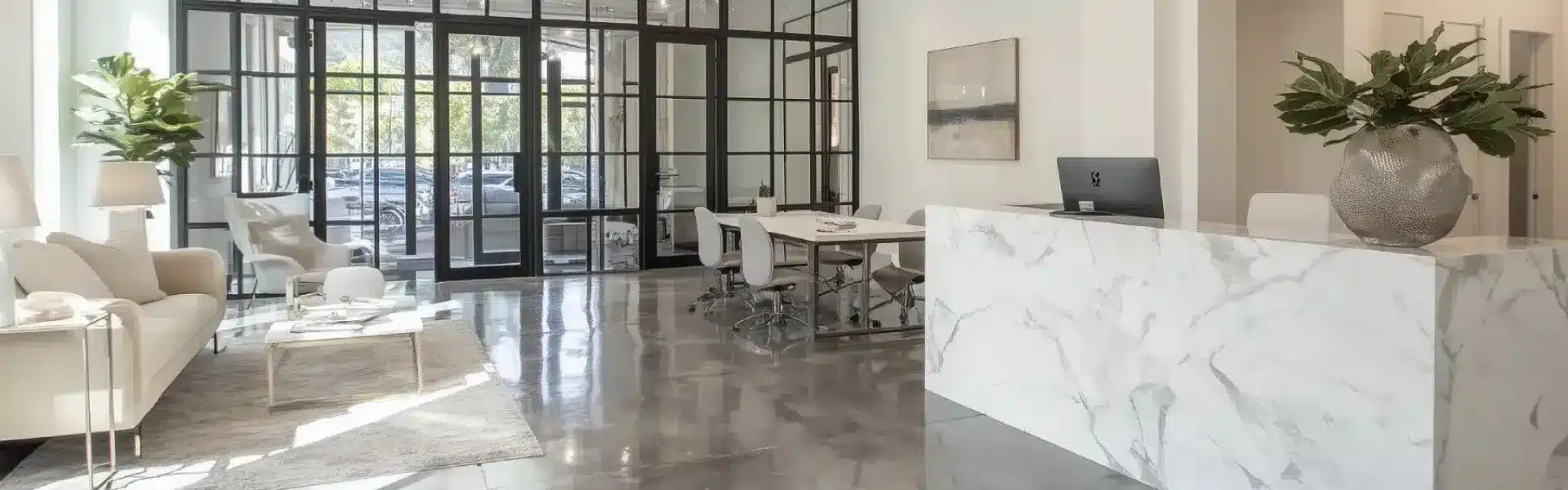 Espace d'accueil moderne d'une agence immobilière de luxe avec comptoir en marbre blanc et éclairage élégant