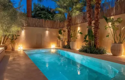 Appartement avec piscine privée à Marrakech, entouré de palmiers illuminés au crépuscule