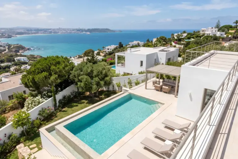 Villa contemporaine blanche avec piscine et transats dominant la baie depuis les hauteurs de Cap Spartel, Tanger