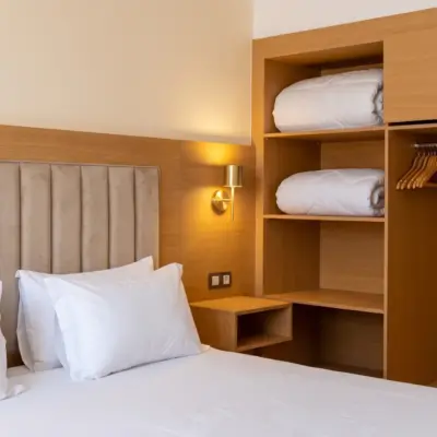 Chambre d'hôtel chaleureuse avec tête de lit capitonnée et penderie à Marrakech