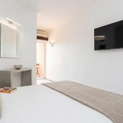 Chambre d'hôtel minimaliste avec téléviseur mural et accès terrasse à Marrakech