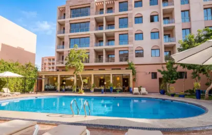Hôtel à vendre à Marrakech avec piscine extérieure, chaises longues et terrasse paysagère.