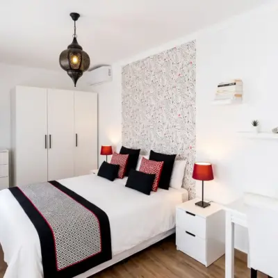 Chambre lumineuse avec penderie blanche et touches rouge et noir dans un riad à Tanger