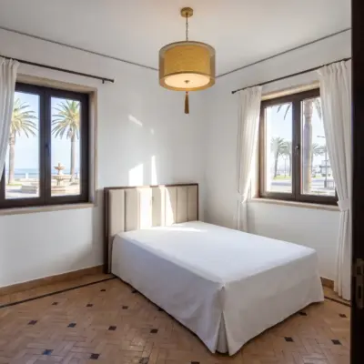 Chambre d'un immeuble à Tanger, avec deux fenêtres donnant sur des palmiers et une fontaine