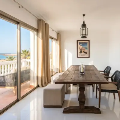 Salle à manger d'un immeuble à Tanger, avec table en bois et baies vitrées vers un balcon vue mer