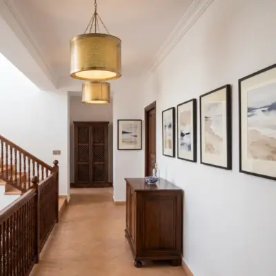Couloir d'un immeuble à Tanger, avec escalier en bois, tableaux encadrés et carrelage en terre cuite