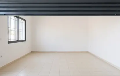 Intérieur d'un garage à louer à Agadir, avec rideau métallique relevé, fenêtre à barreaux et sol carrelé clair