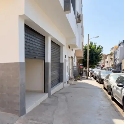 Extérieur d'un garage à Agadir avec rideaux métalliques ouverts et voitures garées le long du trottoir