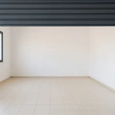 Intérieur vide d'un garage à Agadir, avec murs blancs, plinthes carrelées et sol en carrelage beige