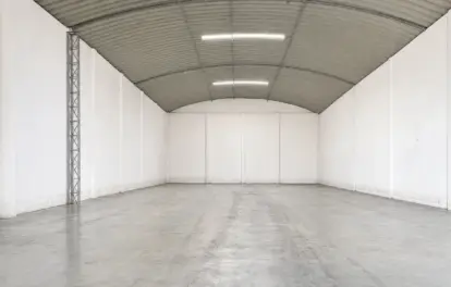Hangar à louer à Bouskoura, avec toiture métallique cintrée, murs à panneaux blancs et sol en béton brut