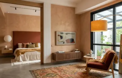 Loft et atelier d’artiste à louer à Asilah, avec séjour, fauteuil rouille, tapis marocain et chambre en alcôve