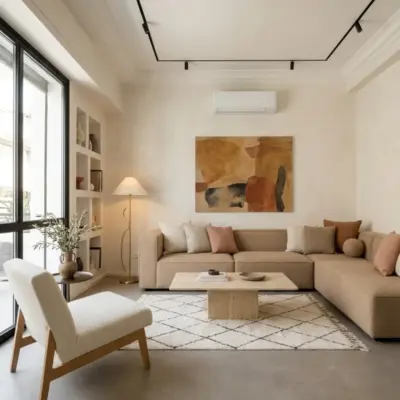 Salon d’un loft à Asilah avec canapé d’angle beige, table basse en travertin, tapis Beni Ouarain et niches murales