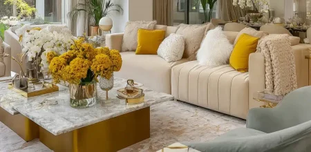 Acheter un appartement à Casablanca : salon luxueux avec canapés crème, table en marbre doré et bouquets de fleurs jaunes.