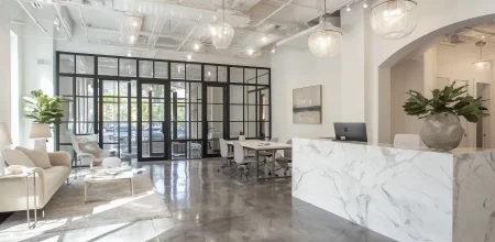 Espace d'accueil moderne d'une agence immobilière de luxe avec comptoir en marbre blanc et éclairage élégant