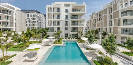 Acheter immobilier Maroc étranger : résidence moderne avec grande piscine, bâtiments blancs et jardins paysagers ensoleillés.