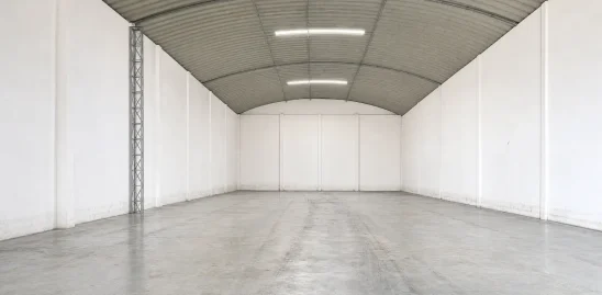 Hangar à louer à Bouskoura, avec toiture métallique cintrée, murs à panneaux blancs et sol en béton brut