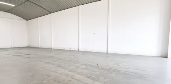 Intérieur d'un hangar à Bouskoura, avec toiture métallique cintrée, double éclairage et poteau en treillis métallique